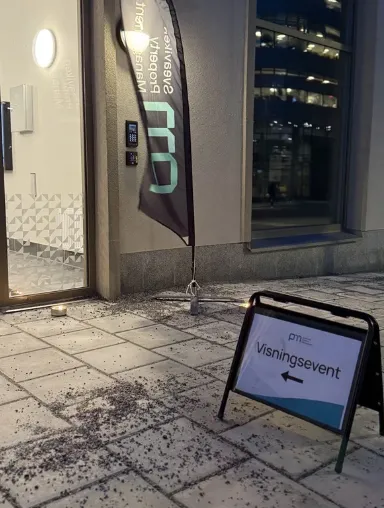 Visningsevent-skylt och Sveaviken PM-beachflagga utanför entrén en kväll