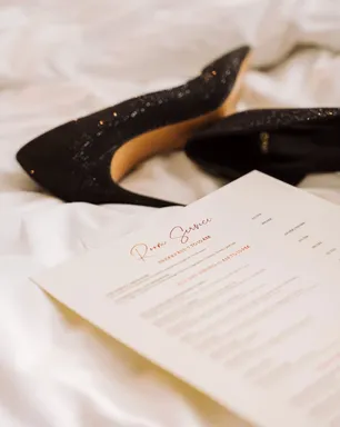 The room service menu on the bed next to a pair of sequined heels