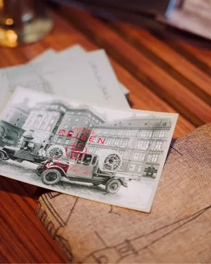 Postcard with a vintage photo of the hotel and Hôtel Reisen's red wordmark, on a wooden table